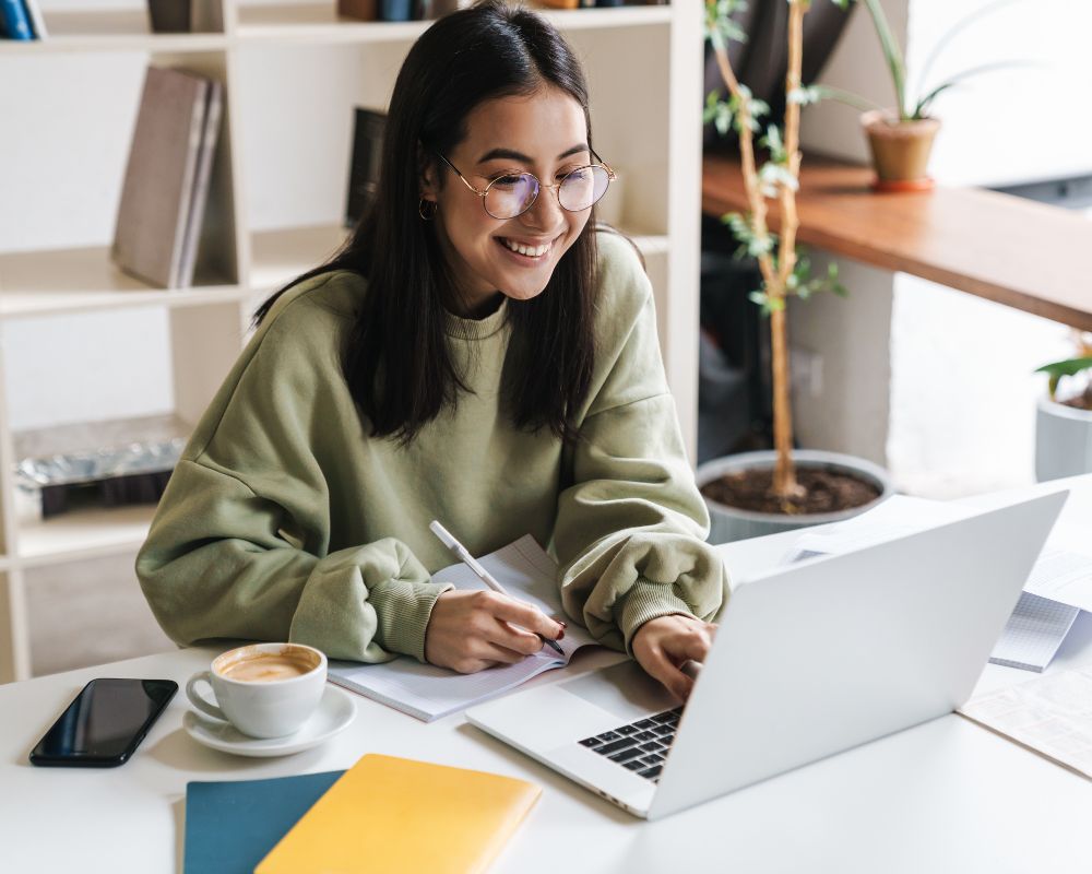 Mujer escribiendo y organizando los primeros pasos de la publicación de su libro frente a una laptop.