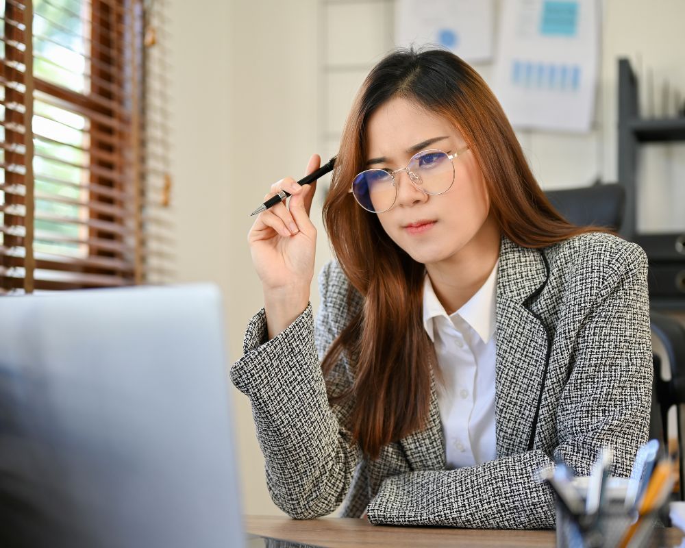 Mujer concentrada mirando la computadora mientras toma una decisión sobre cómo publicar su libro.