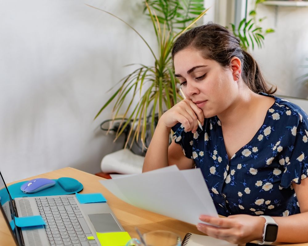 Mujer analizando documentos y pensando cómo definir el proyecto de un libro antes de publicar.